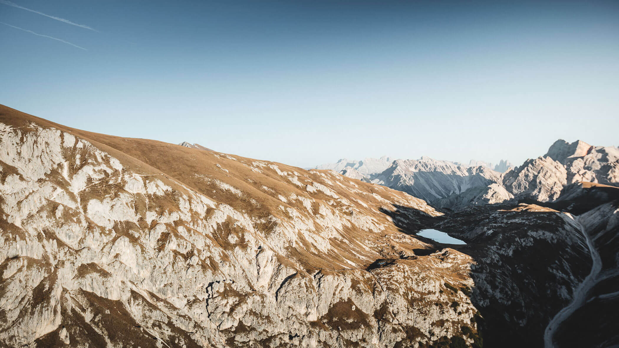 Berglandschaft mit felsigen Hängen, einem kleinen See und klarem, blauem Himmel im Hintergrund. - Kerschbaumerhof